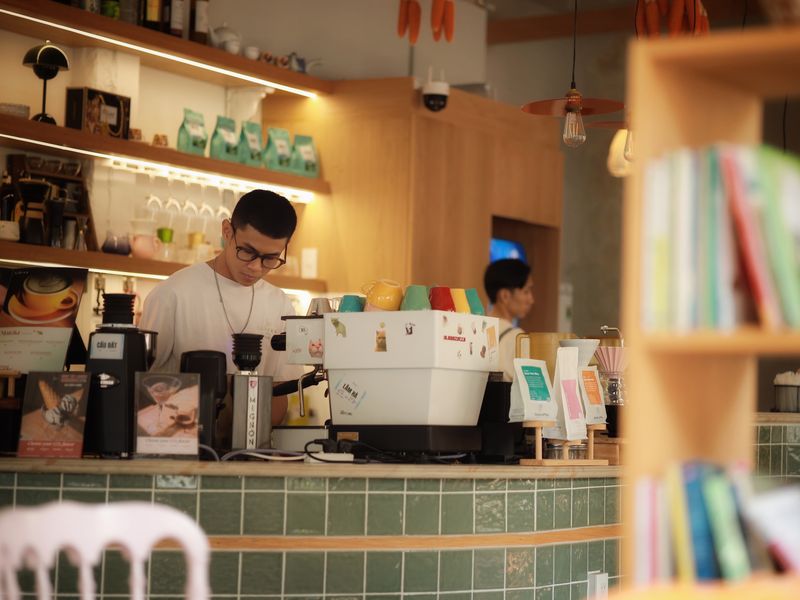 在溫暖燈光的咖啡館裡，店員正在沖煮咖啡