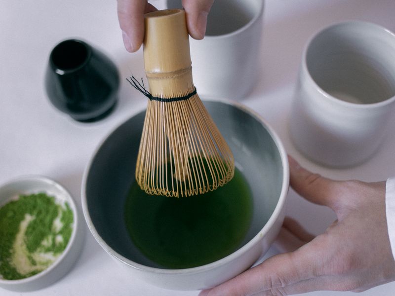 雙手用竹製茶筅在陶碗裡刷抹茶